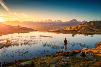Sunrise shines over Lac Guichard with Arves massif, Male hiker in French Alps at Savoie, France